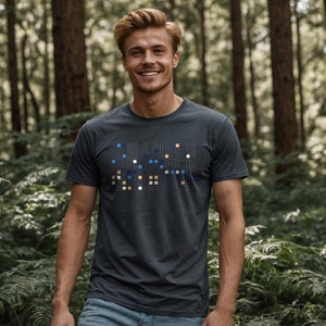 Peut inclure: Un t-shirt bleu foncé avec un motif pixélisé dans des tons de bleu, jaune et blanc. Le motif indique "GREEN" dans une police stylisée.