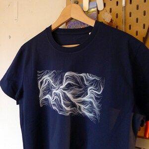 Könnte beinhalten: Ein marineblaues T-Shirt mit einem weißen abstrakten Design aus wirbelnden Linien.