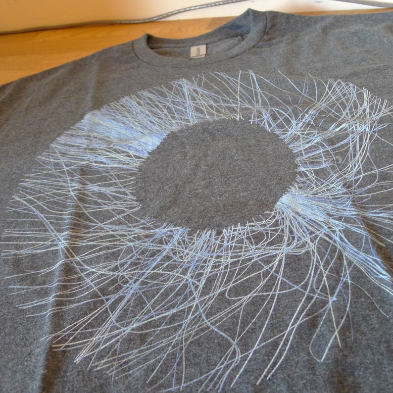 Angled close-up of the upper portion of the blue radial circle print showing the fine generative lines against the dark fabric