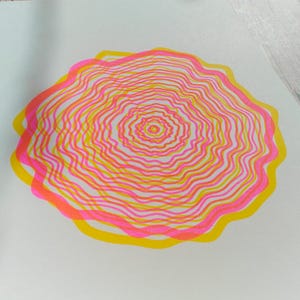 Detail of the A5 riso print with visible colour overlap, concentric tree rings in pink and yellow