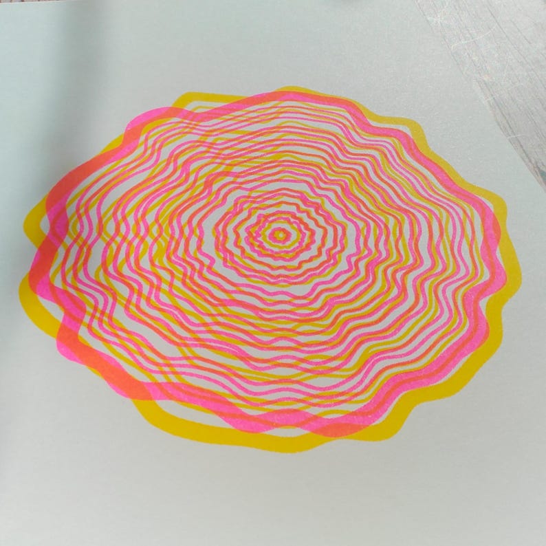 Detail of the A5 riso print with visible colour overlap, concentric tree rings in pink and yellow