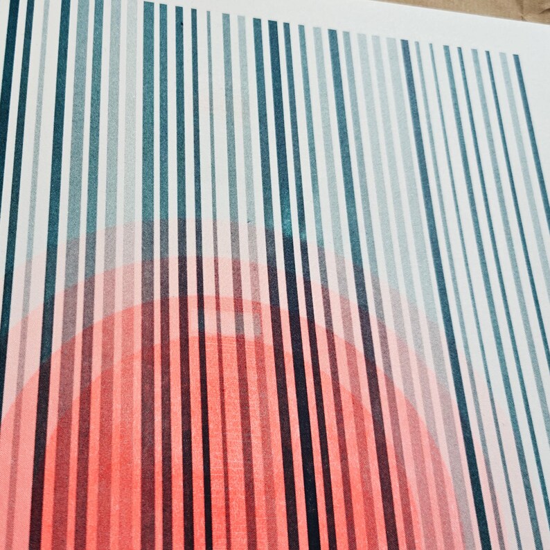 Angled close-up of the riso print showing the grainy texture of the teal stripes over the fluorescent orange circle