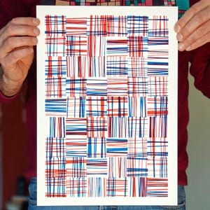 Könnte beinhalten: Ein weißer Druck mit einem geometrischen Muster aus roten und blauen Linien. Die Linien sind in einem gitterartigen Muster angeordnet, wodurch eine Reihe von Quadraten und Rechtecken entsteht.