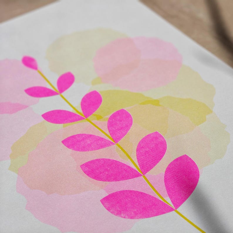 Angled close-up of the pink botanical riso print showing the grainy ink texture of the leaves and pastel layers