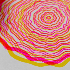 Macro detail of the A5 riso print, concentric tree rings in pink and yellow