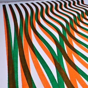 Macro detail of the abstract riso print with intersecting green, orange and brown wavy lines printed on white paper