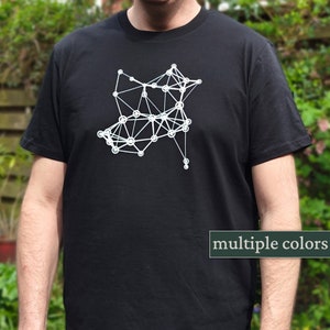 Op de afbeelding: Een zwart T-shirt met een wit geometrisch ontwerp op de voorkant. Het ontwerp bestaat uit verbonden cirkels en lijnen. Het shirt is verkrijgbaar in meerdere kleuren.