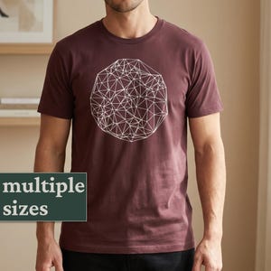 Peut inclure: Un t-shirt bordeaux avec un motif géométrique blanc sur le devant. Le t-shirt a des manches courtes et un col rond. Le texte "multiple sizes" est affiché sur un rectangle vert foncé en bas à gauche.