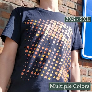 Op de afbeelding: Een zwart T-shirt met een geometrisch patroon in oranje en gele tinten. Het patroon bestaat uit cirkels, vierkanten en driehoeken. Het shirt is verkrijgbaar in de maten 2XS tot 5XL. Meerdere kleuren.