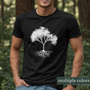 Peut inclure: Un t-shirt noir avec une silhouette blanche d'un arbre avec des racines. L'arbre a un design simple avec de nombreuses branches et un tronc épais. Les racines sont étalées et détaillées.