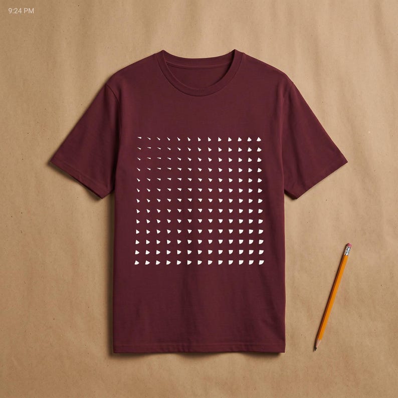 Burgundy t-shirt with the white generative triangle grid print, flat lay on kraft paper with a pencil beside it