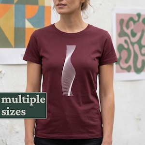 Op de afbeelding: Bordeauxkleurig T-shirt met ronde hals en een wit, abstract, gebogen ontwerp. Het shirt met korte mouwen is gemaakt van zacht materiaal. De tekst "multiple sizes" wordt weergegeven op een donkergroene rechthoek.