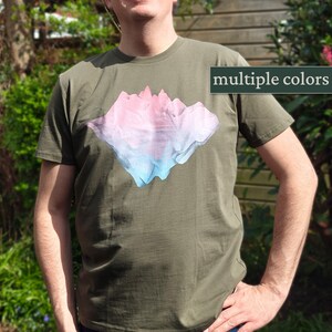 Könnte beinhalten: Ein grünes T-Shirt mit einem Aufdruck einer Bergkette in Rosa, Blau und Weiß. Der Text "multiple colors" ist in der oberen rechten Ecke des Bildes sichtbar.