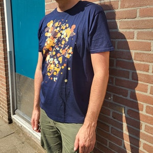 May include: A navy blue t-shirt with a colorful abstract print of yellow, orange, and brown circles.