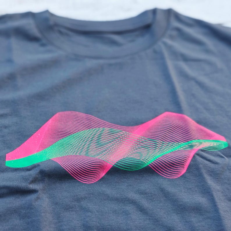 Close-up of the neon pink and green wavy line surface print on a grey t-shirt