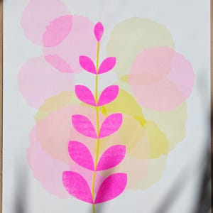 The full A3 botanical riso print — a fluorescent pink leaf sprig over soft pink and yellow watercolour-like circles on white paper