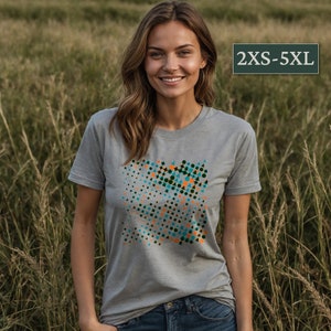 Könnte beinhalten: Ein graues T-Shirt mit einem geometrischen Muster in den Farben Türkis, Orange und Schwarz. Das Muster besteht aus Kreisen, Dreiecken und Quadraten. Das Shirt ist in den Größen 2XS-5XL erhältlich.