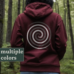 Op de afbeelding: Een bordeauxrode hoodie met een wit en grijs spiraalontwerp op de rug.