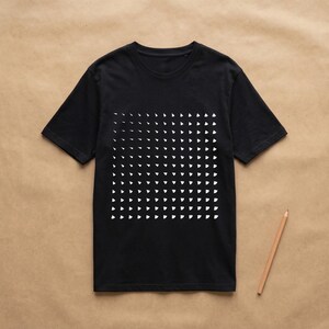 Black t-shirt with the generative white triangle pattern, flat lay on kraft paper with a pencil