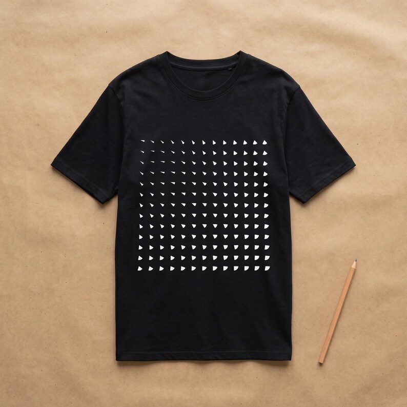 Black t-shirt with the generative white triangle pattern, flat lay on kraft paper with a pencil