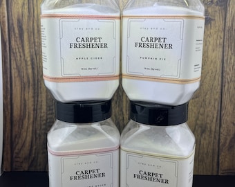 May include: Four clear plastic jars with black lids containing white powder. Each jar has a label that reads "clay and co. CARPET FRESHENER" with a different scent: Apple Cider, Pumpkin Pie, Peppermint Stick, and Harmony. Each jar is 16 oz. (by vol.)