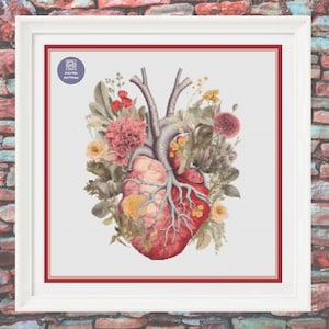 Op de afbeelding: Een kruissteekpatroon met een gedetailleerd anatomisch hart, omringd door kleurrijke bloemen en groen. Het hart is rood en roze, met zichtbare aderen en slagaders. De bloemen zijn een mix van geel, roze en paars.