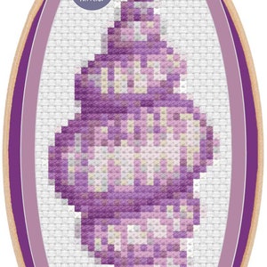 May include: A cross-stitch pattern of a seashell in shades of purple, lavender, and white, displayed in an embroidery hoop. The design is pixelated, with a digital pattern label.