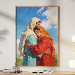 Könnte beinhalten: Ein gerahmtes Gemälde zeigt zwei Figuren, die sich umarmen, vor einem blauen Himmel mit Wolken. Die Figuren sind in farbenfrohe Stoffe gehüllt: Weiß, Blau und Rot. Das Gemälde hängt über einem Holzschrank.