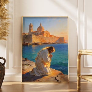 Könnte beinhalten: Ein gerahmter Druck einer religiösen Szene. Das Kunstwerk zeigt eine kniende Figur am Meer, mit einer Stadt und Booten im Hintergrund. Die Farbpalette umfasst Blau-, Orange- und Gelbtöne und erzeugt eine warme und heitere Atmosphäre.