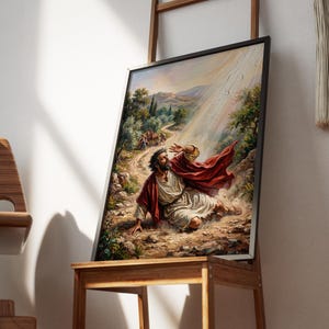 Könnte beinhalten: Ein gerahmter Kunstdruck, der eine biblische Szene darstellt. Das Kunstwerk zeigt einen Mann in weißem Gewand und rotem Umhang, der auf einem felsigen Pfad stürzt. Der Hintergrund zeigt eine Straße, Bäume und Figuren, mit einem Lichtstrahl.