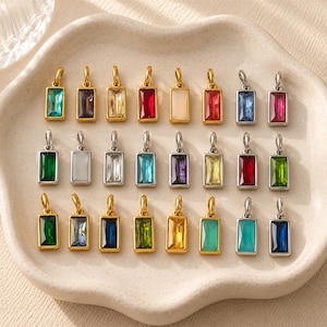 Peut inclure: Une collection de pendentifs rectangulaires avec des pierres précieuses facettées de diverses couleurs, dont le rouge, le bleu, le vert, le jaune et le transparent, serties dans des cadres en métal doré et argenté avec des anneaux de fixation.