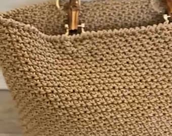 May include: A woven straw tote bag with bamboo handles. The bag is a light brown color and has a woven texture.