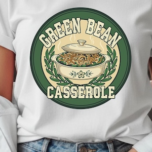Puede incluir: Camiseta blanca con un gráfico circular. El gráfico presenta las palabras "GREEN BEAN CASSEROLE" alrededor de una ilustración de cazuela en verde y crema. La camiseta la lleva una persona.
