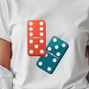 Puede incluir: Camiseta blanca con un gráfico de dos dominós. Un dominó es rojo con puntos blancos, y el otro es verde azulado con puntos blancos. La camiseta está hecha de un material suave y es adecuada para uso casual.