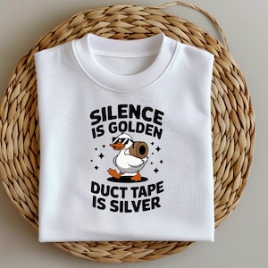 Puede incluir: Camiseta blanca con un gráfico negro de un pato con gafas de sol y llevando un rollo de cinta adhesiva. El texto "Silence is Golden Duct Tape is Silver" está impreso en la camiseta.