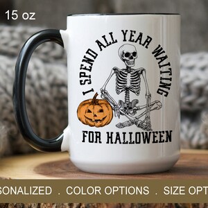 May include: White ceramic coffee mug with a black handle. The mug features a skeleton sitting with a pumpkin and the text "I spend all year waiting for Halloween".