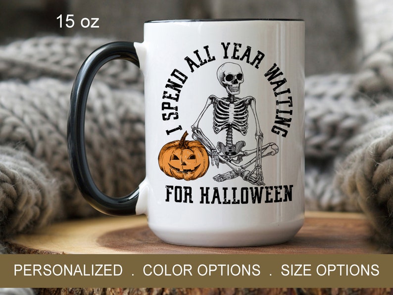 May include: White ceramic coffee mug with a black handle. The mug features a skeleton sitting with a pumpkin and the text "I spend all year waiting for Halloween".