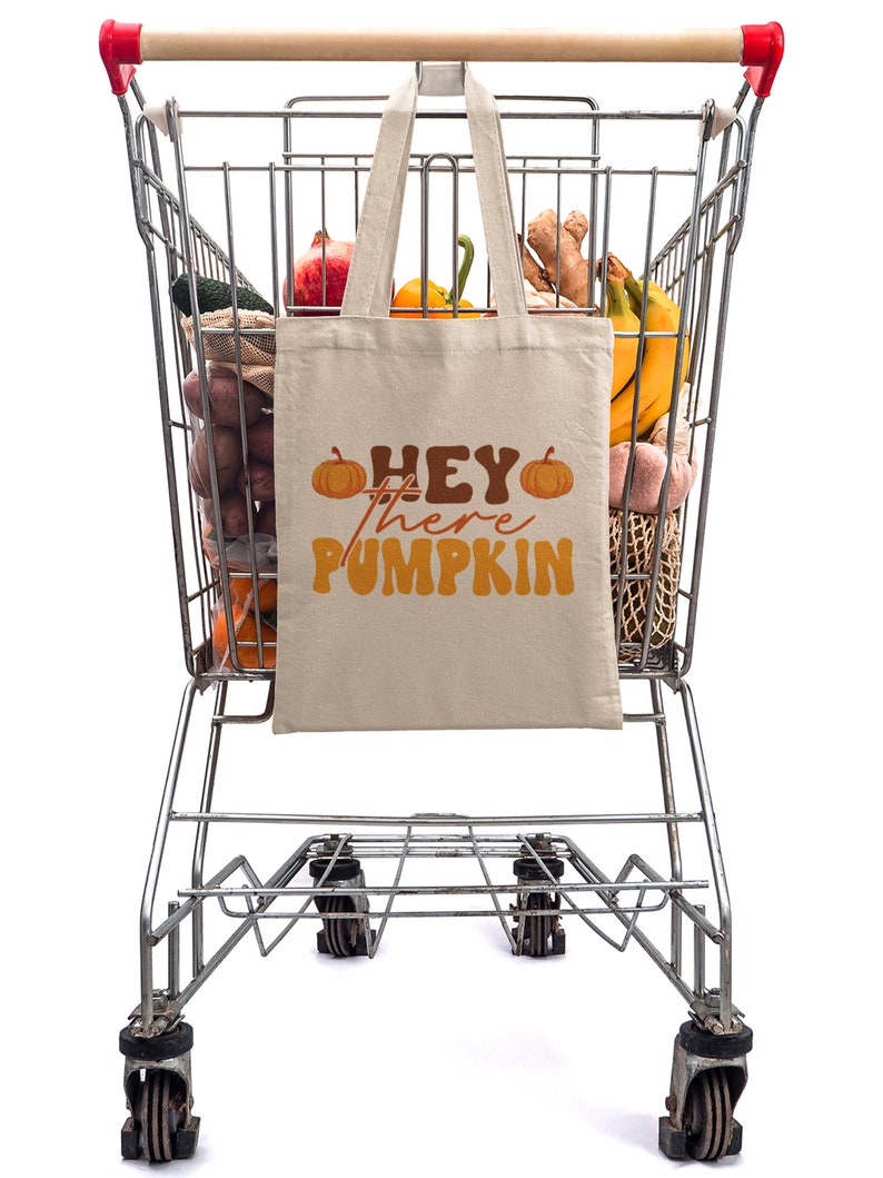 May include: A shopping cart filled with groceries, including produce, bananas, and a reusable tote bag with the text "Hey there Pumpkin" printed on it.
