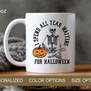 May include: White ceramic mug with a black skeleton holding a pumpkin and the text "I spend all year waiting for Halloween". The mug is 11 ounces.