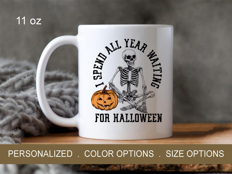 May include: White ceramic mug with a black skeleton holding a pumpkin and the text "I spend all year waiting for Halloween". The mug is 11 ounces.