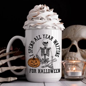 May include: White coffee mug with a black skeleton sitting cross-legged and holding a pumpkin. The mug reads "I spend all year waiting for Halloween".