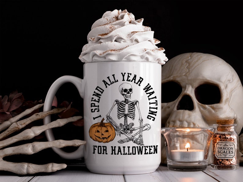 May include: White coffee mug with a black skeleton sitting cross-legged and holding a pumpkin. The mug reads "I spend all year waiting for Halloween".