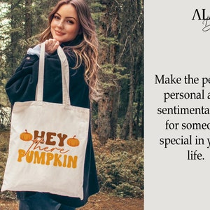May include: A white tote bag with the text "HEY there PUMPKIN" in orange and brown lettering. The bag is decorated with two orange pumpkins.