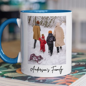 Puede incluir: Taza de cer&aacute;mica blanca con asa azul. La taza presenta una foto de una familia de cuatro personas caminando en la nieve. El texto "Anderson's Family" est&aacute; impreso en la parte inferior de la taza.