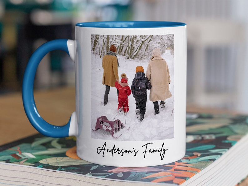 Puede incluir: Taza de cer&aacute;mica blanca con asa azul. La taza presenta una foto de una familia de cuatro personas caminando en la nieve. El texto "Anderson's Family" est&aacute; impreso en la parte inferior de la taza.
