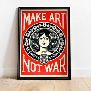 Può includere: Un poster incorniciato con sfondo rosso e testo nero che recita "Make Art Not War". Il poster presenta un'illustrazione in bianco e nero del viso di una donna con rose nei capelli.