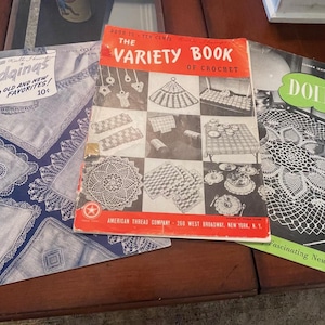 May include: Three vintage crochet pattern books with colorful covers. The first book is blue with white crochet designs and the text "Edgings 100 Old and New Favorites! 10c". The second book is red with white and black crochet designs and the text "The Variety Book of Crochet". The third book is green with white crochet designs and the text "Doilies Fascinating New Designs".