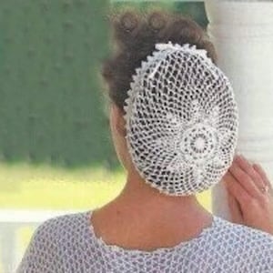 May include: White crocheted hairnet with a circular design. The hairnet is worn by a person with brown hair.