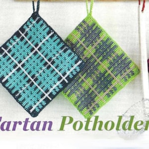 May include: Three crocheted pot holders in a tartan pattern. The pot holders are green, blue, and pink. The pot holders are hanging from a wooden dowel.