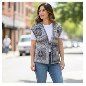 May include: A grey and white crochet vest with a tie fastening. The vest is worn over a white t-shirt and paired with blue jeans. The crochet pattern features a floral design.